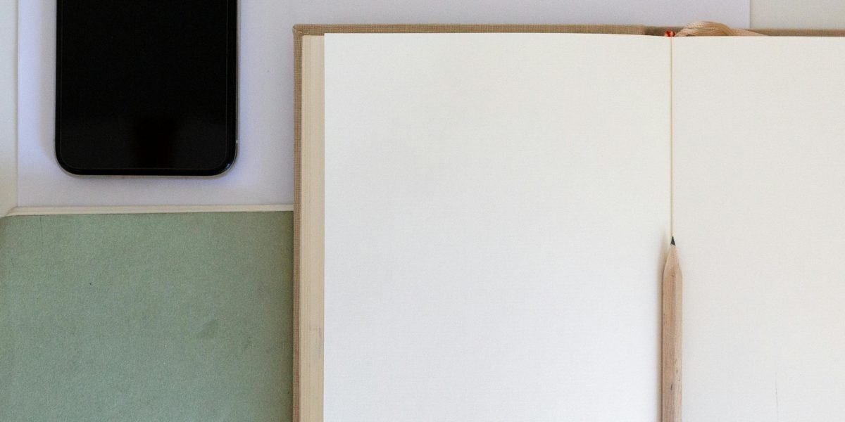 Notebook and laptop on desk for writing about AI