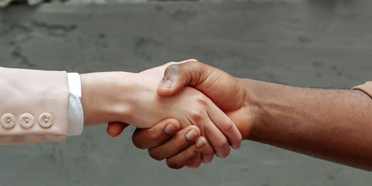 Two professionals shaking hands, symbolizing agreement, trust, and successful collaboration in building reliable AI through strong governance.
