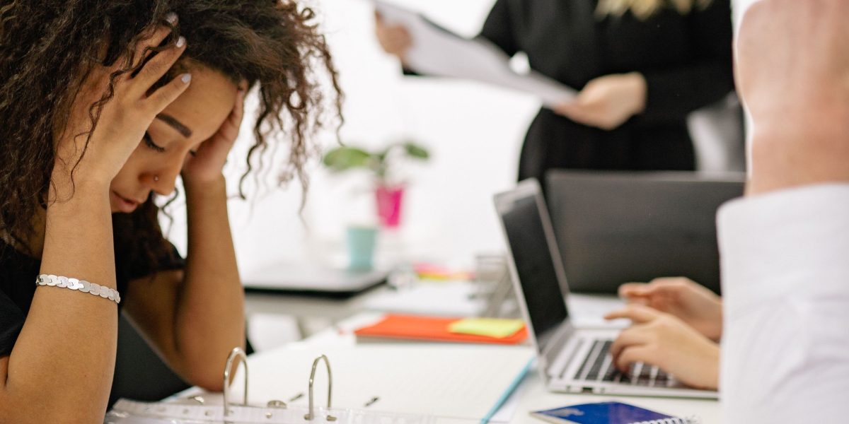 A visibly stressed business professional in a meeting setting, perhaps discussing challenging outcomes or difficult decisions.